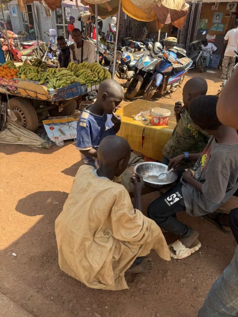 Niños compartiendo comida en un mercado de Kedougou